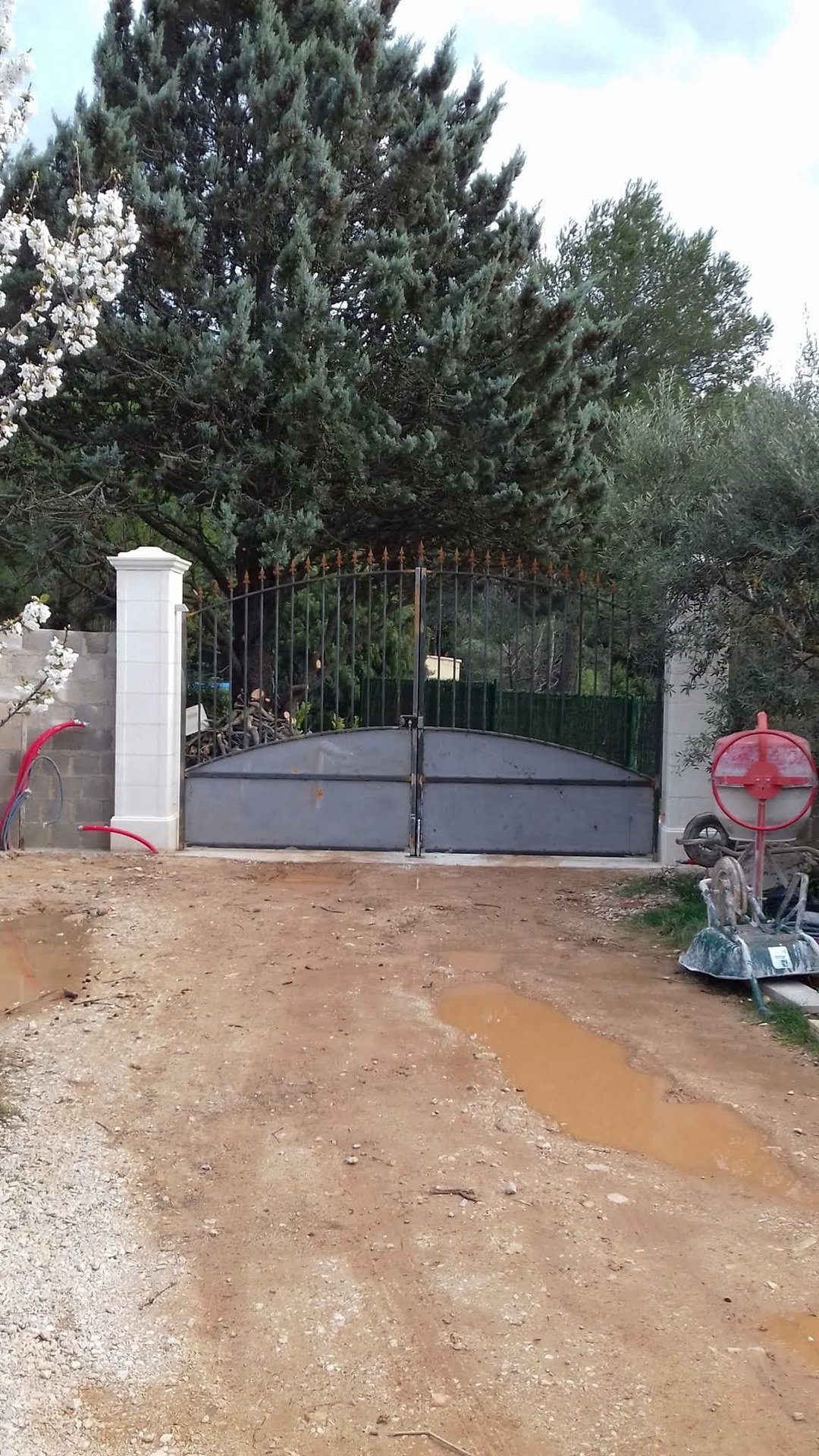 Construction d'un mur de clôture en parpaings avec piliers enduits et portail métallique