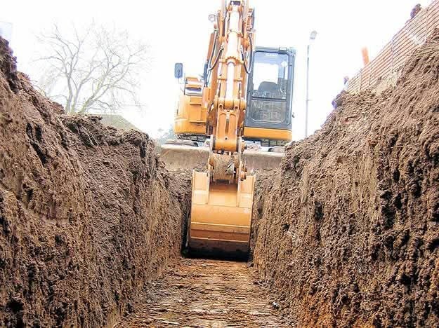 Excavatrice réalisant des fouilles en tranchée profonde pour réseaux enterrés